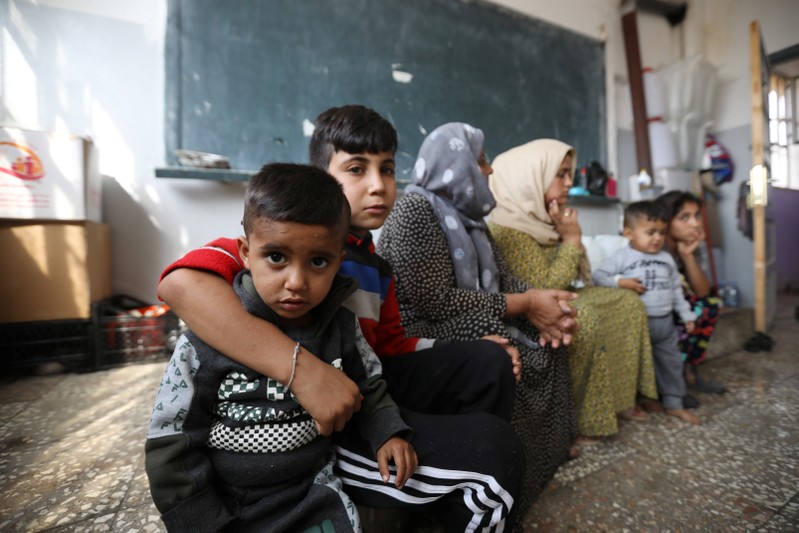 Displaced Kurdish children, who fled from violence with their family after a Turkish offensive in northeastern Syria, sit in a class roome at a public school used as shelter where they live now in Hasakah