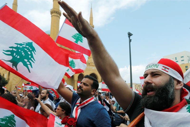 Demonstrators carry national flags and gesture during an anti-government protest in downtown Beirut