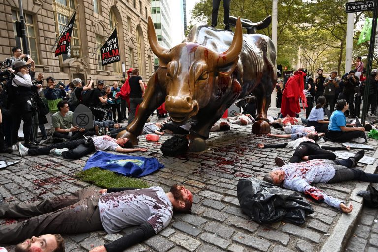 Protesters stage ‘die-in’ at Wall Street bull statue, cover it with blood and climb atop it