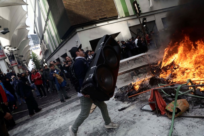 FILE PHOTO: A man prepares to throw a speaker into a burning barricade while vandalizing a shop during a protest against Chile's state economic model in Concepcion