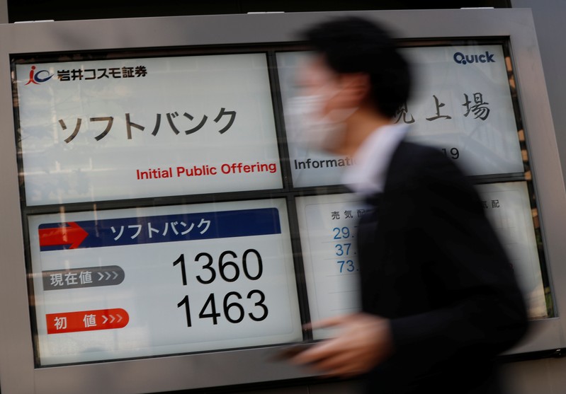 A man walks past in front of a stock quotation board showing the price of the SoftBank Corp. on the Tokyo Stock Exchange outside a brokerage in Tokyo
