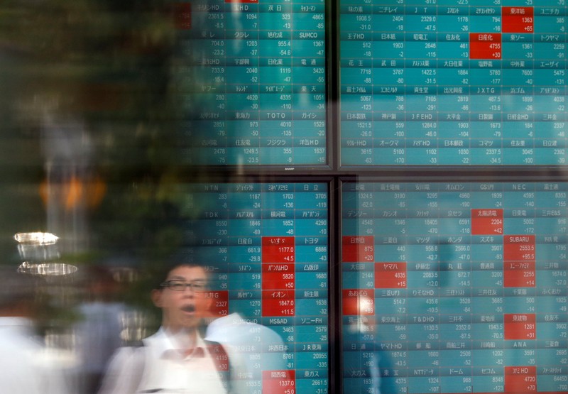 A man is reflected on a stock quotation board outside a brokerage in Tokyo
