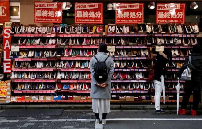 FILE PHOTO: A woman looks at shoes on sale at an outlet store in Tokyo's shopping district