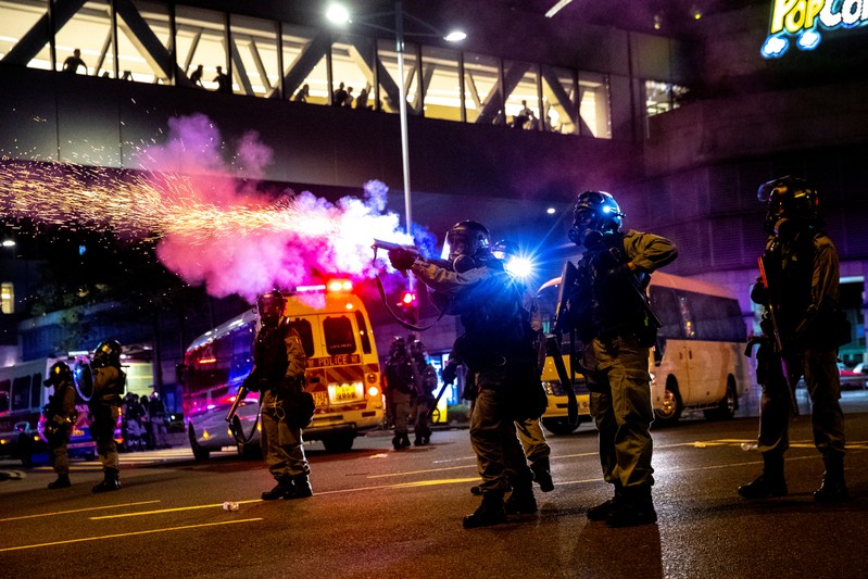 FILE PHOTO: A riot police officer fires a tear gas canister toward anti-government protesters during a demonstration in the Tseung Kwan O residential area in Kowloon, Hong Kong