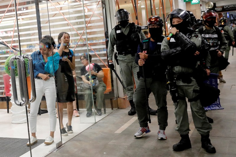 A woman tries to hear the police's warning message, at a shopping mall in Tai Po in Hong Kong