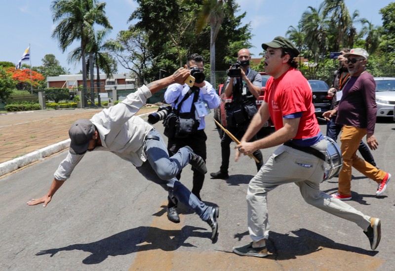 A supporter of Venezuela's President Nicolas Maduro fights with an opposition leader Juan Guaido's supporter outside Venezuelan embassy in Brasilia
