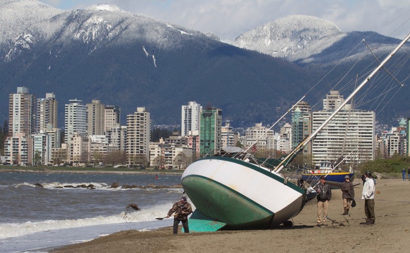 Boat owner digs out his boat stranded on English Bay after wind storm blew them ashore in Vancouver