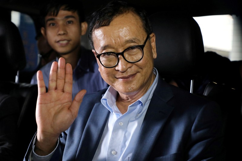 Cambodia's self-exiled opposition party founder Sam Rainsy waves before he leaves Kuala Lumpur International Airport in Sepang
