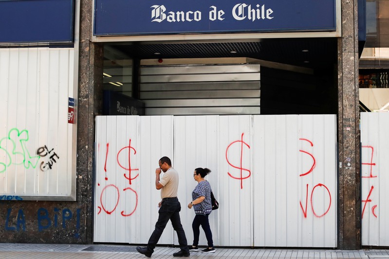 People walk past a closed bank agency in Santiago