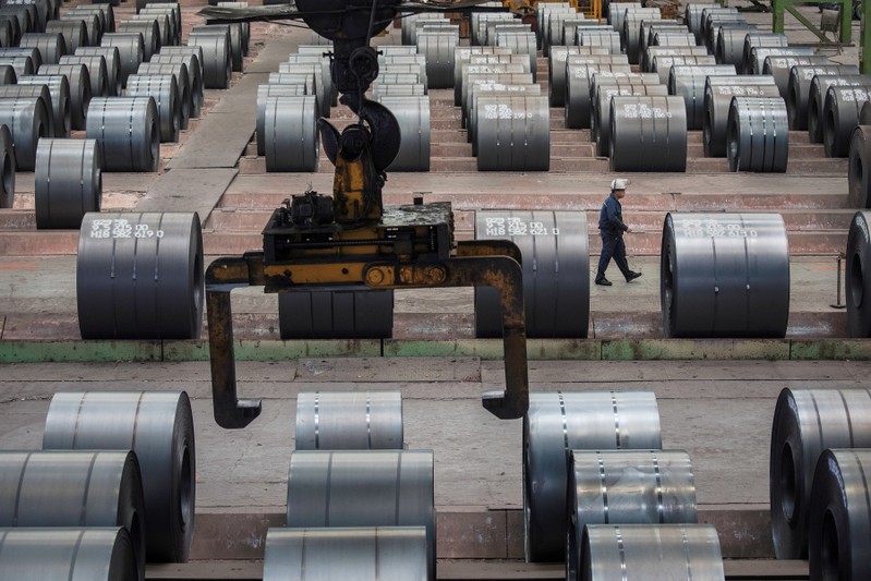 FILE PHOTO: Worker walks past steel rolls at the Chongqing Iron and Steel plant in Changshou