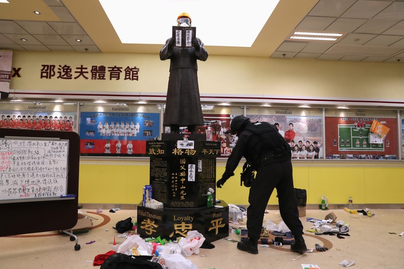 Member of a safety team established by police and local authorities inspects around a statue of Dr Sun Yat-sen, as they assess and clear unsafe items at the Hong Kong Polytechnic University (PolyU) in Hong Kong