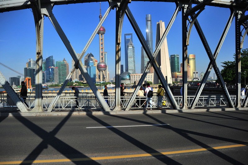 People walk on a bridge near the financial district of Pudong in Shanghai