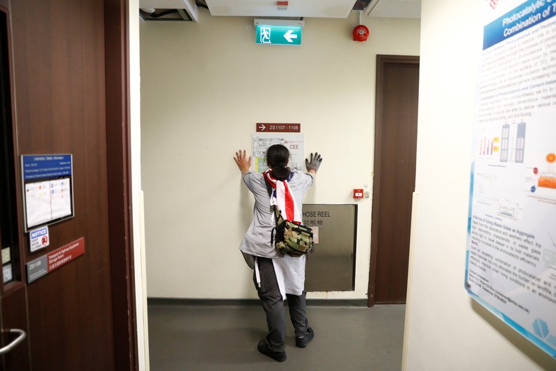 A protester looks at a floor plan of a building during a search for fellow protesters who might be hiding, at the Hong Kong Polytechnic University (PolyU)