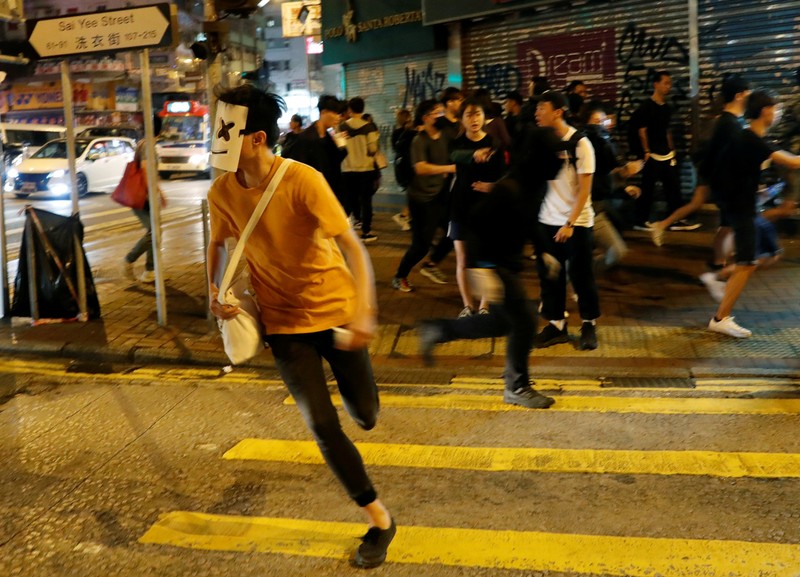 An anti-government protester wearing a Halloween mask runs as riot policemen advance to disperse protesters during Halloween in Hong Kong