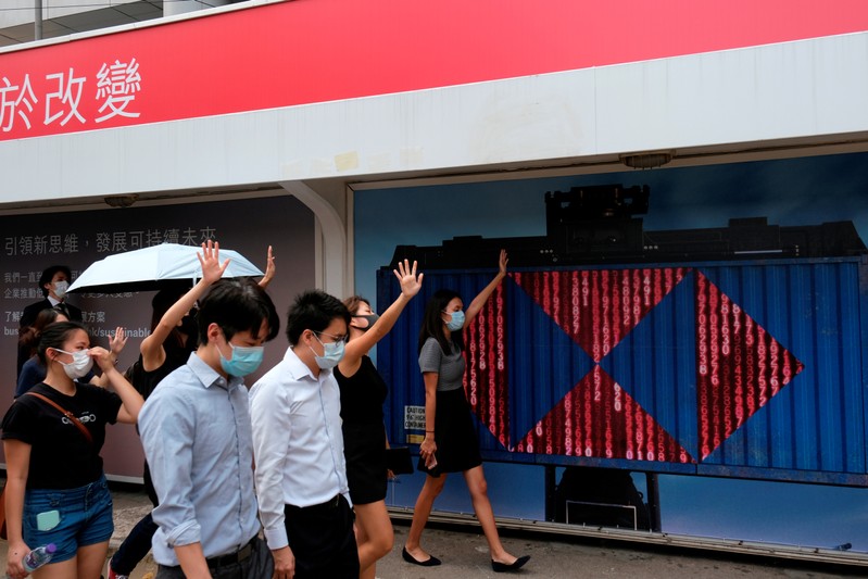 FILE PHOTO: Anti-government demonstrators walk past a board with the logo of HSBC during a flash mob protest after violent China's National Day protests, at Central, in Hong Kong
