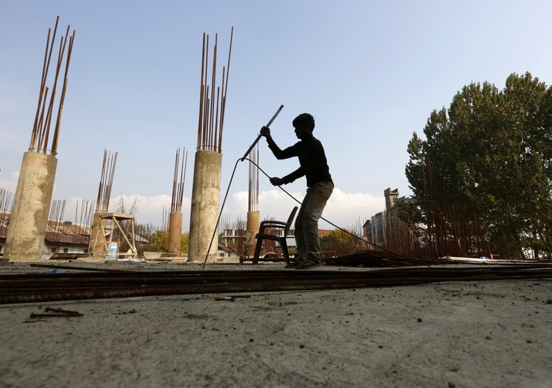 A migrant worker straightens an iron rod at the construction site of a parking lot in Srinagar