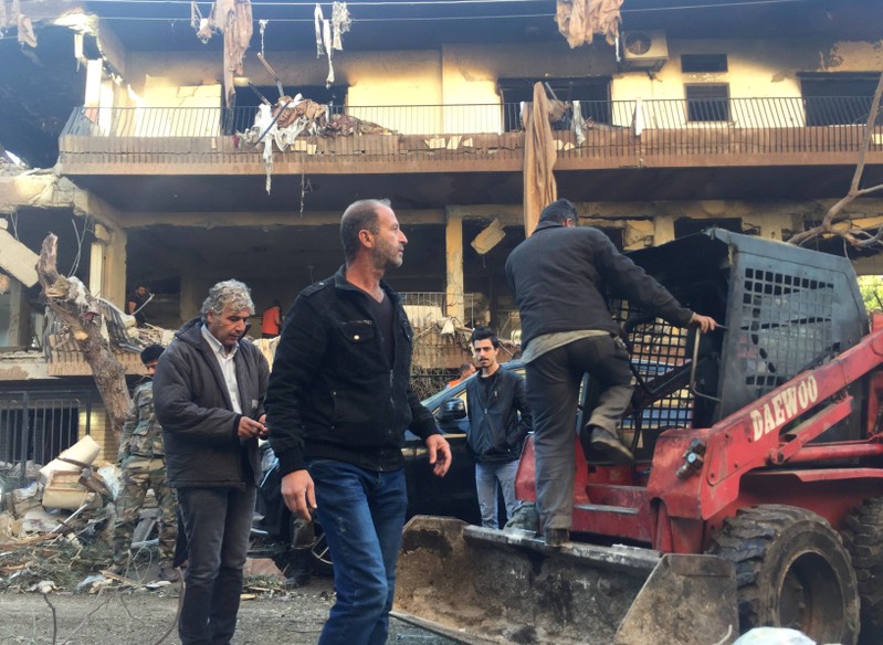 People walk past a damaged building in Mezzah