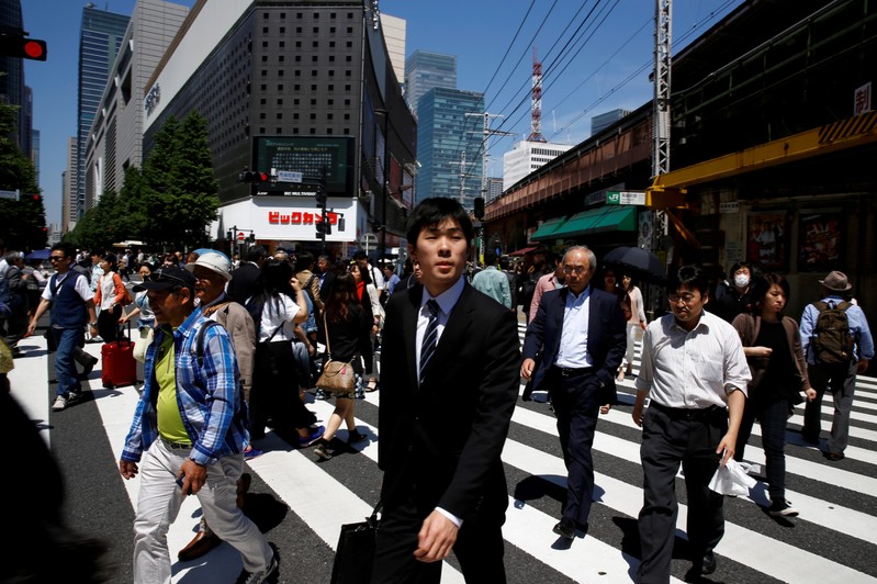 FILE PHOTO: People cross a junction in front of an electronics retailer in a business district in Tokyo