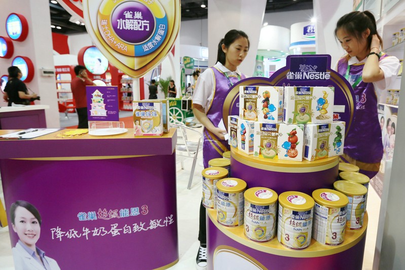 FILE PHOTO: Staff members are seen at the booth of Nestle promoting its baby food at a maternity and baby industry fair in Beijing