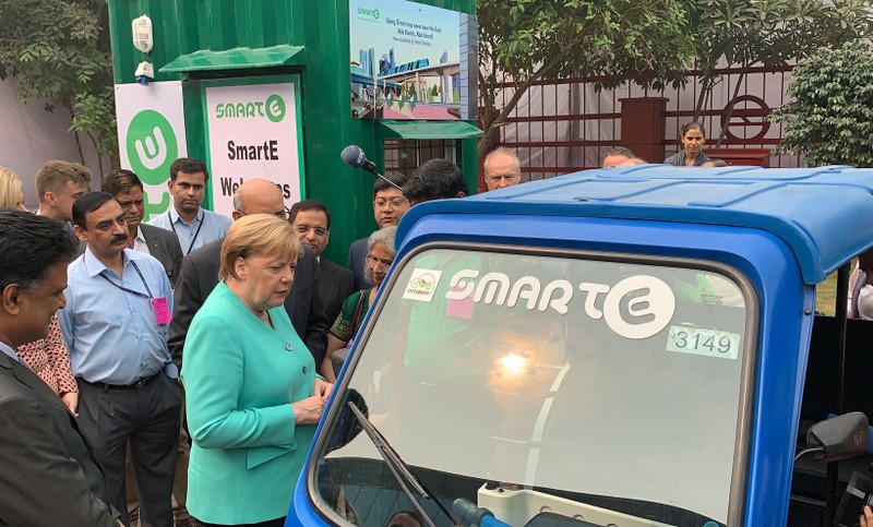 FILE PHOTO: German Chancellor Angela Merkel stands next to an electric vehicle during her visit to a solar powered metro station at Dwarka in New Delhi