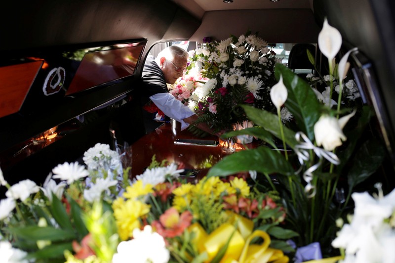 A man puts flowers inside a hearse of one of the victims of a mass shooting at a Walmart store during a tribute in El Paso