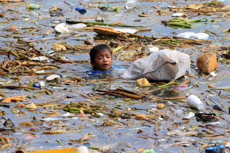 FILE PHOTO: A boy swims as he collects recyclable plastic bottles drifting with garbage along the coast of Manila Bay at the slum area in the Baseco Compound in metro Manila