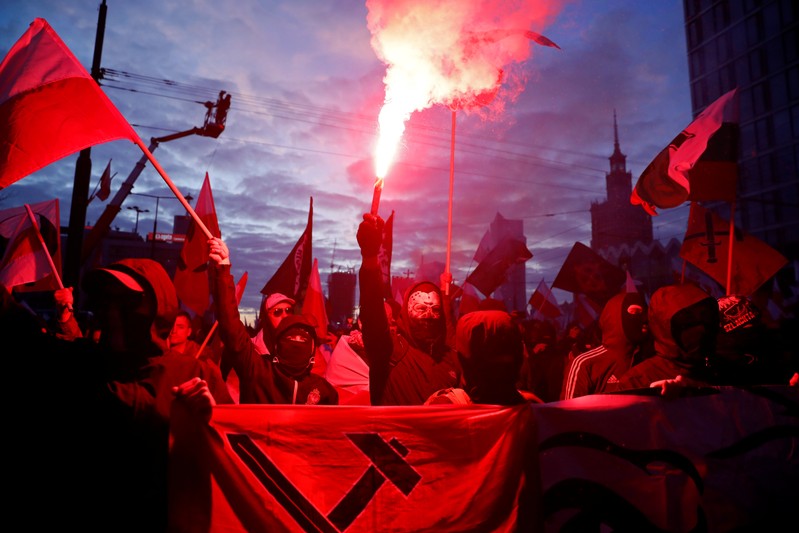 People carry Polish flags and flares during a march marking the 101st anniversary of Polish independence in Warsaw