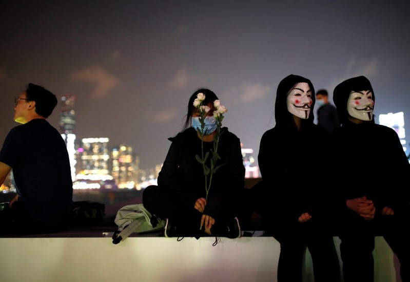 A woman holds flowers at Tamar Park, outside the Legislative Council (Legco) building, during a prayer and remembrance ceremony in Hong Kong