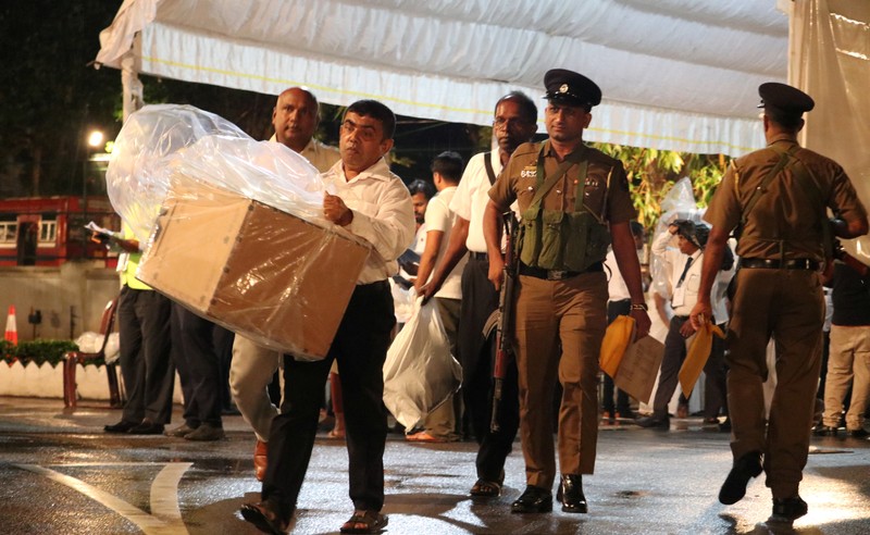 Election officials, assisted by Sri Lankan police officer, arrive with a ballot box to a counting center, after the voting ended during the presidential election day, in Colombo