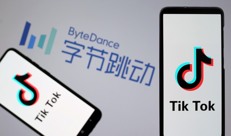 Tik Tok logos are seen on smartphones in front of displayed ByteDance logo in this illustration