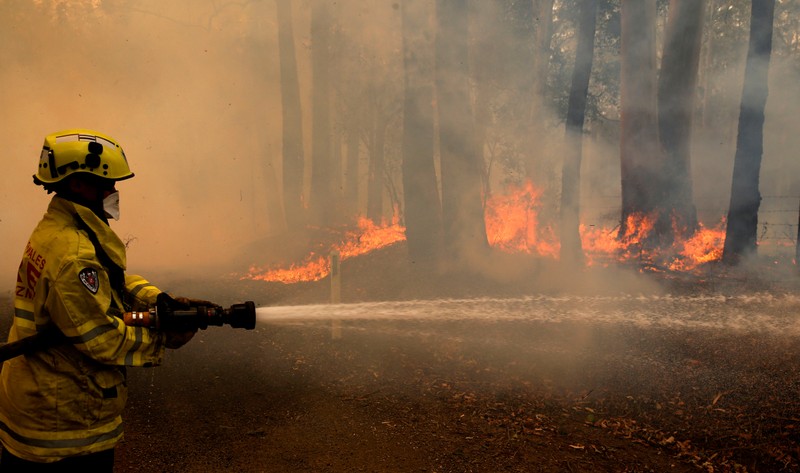 A Gloucester fire crew member fights flames from a bushfire at Koorainghat