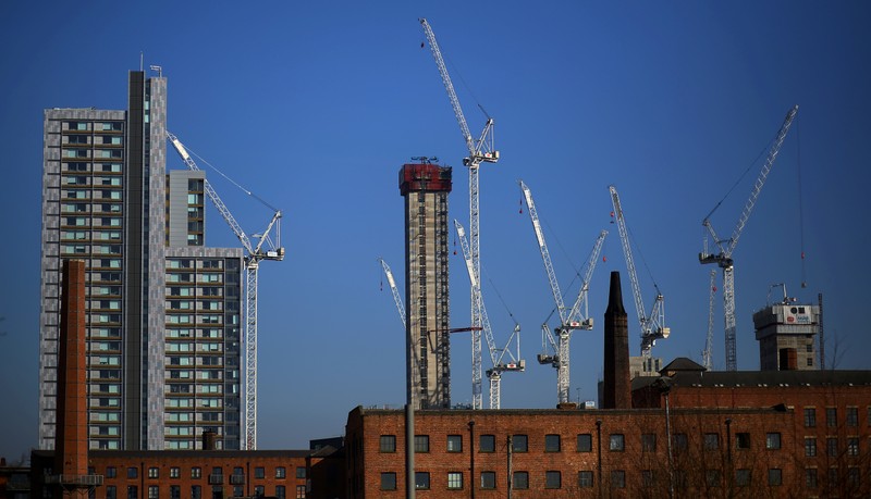Construction cranes are seen above a refurbished Mill building in the city centre of Manchester