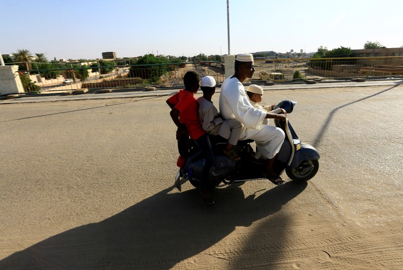 A Sudanese family rides a motorbike on a railway bridge in Atbara at the Nile State
