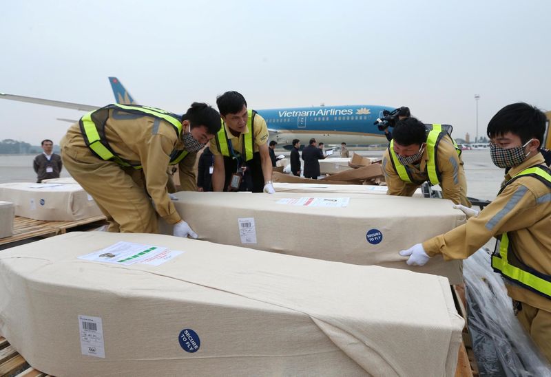 Airport workers unload coffins, carrying some of the 39 bodies found on a truck container in Britain, from an airplane for homeland repatriation at Noi Bai airport in Hanoi