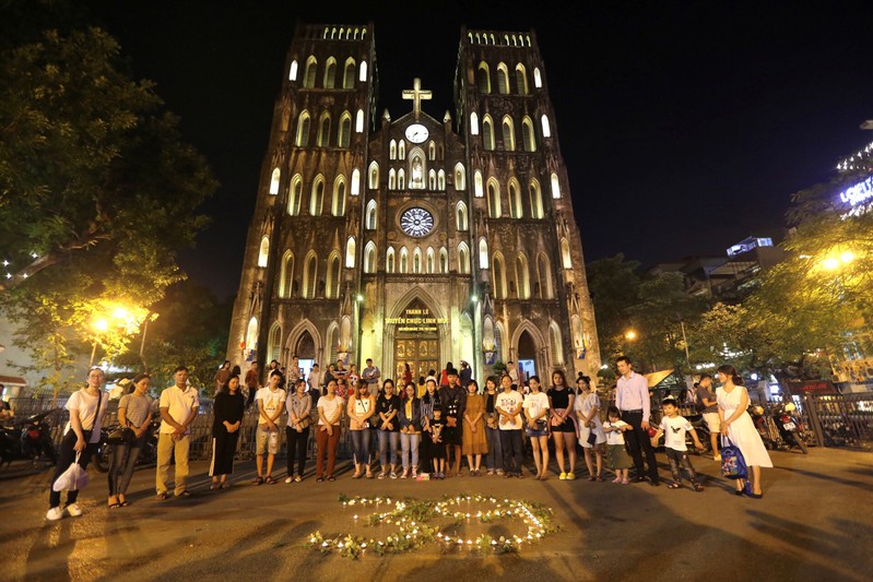 Residents light candles to pray for 39 people found dead in the back of a truck near London, in front of Hanoi Cathedral in Hanoi