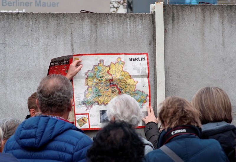 People watch a map of the divided West and East Berlin shown on remains of the Berlin Wall at the Wall memorial on Bernauer Strasse in Berlin
