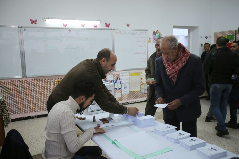 A voter receives ballots at a polling station during the presidential election in Algiers