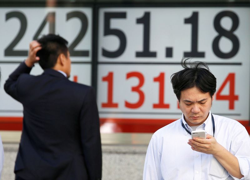 Men stand in front of an electronic board showing Japan's Nikkei average outside a brokerage in Tokyo