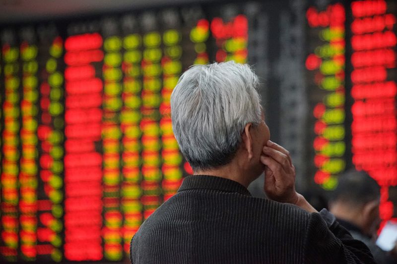 An investor looks at an electronic board showing stock information at a brokerage house in Nanjing