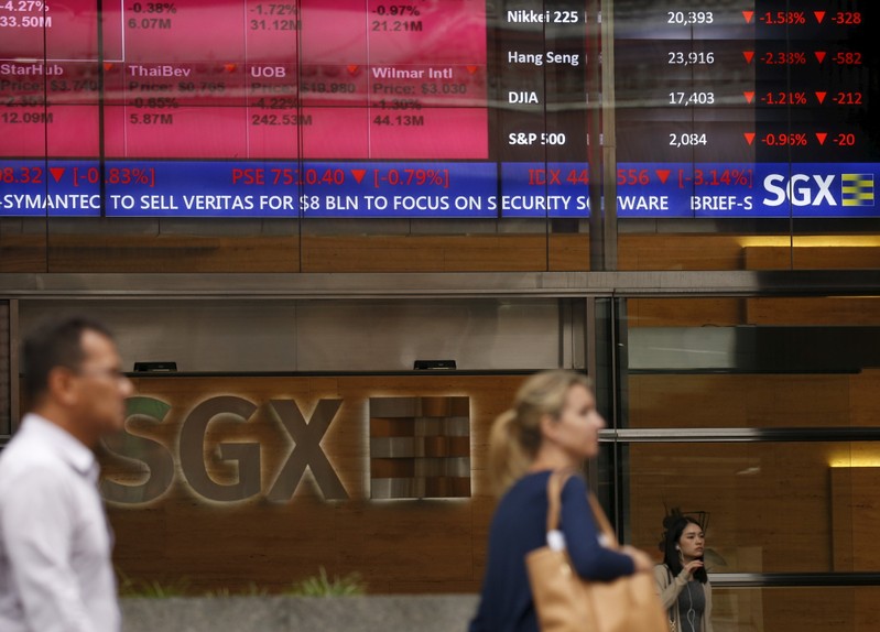 People pass a stock board showing stocks in red outside the Singapore Exchange in the central business district in Singapore