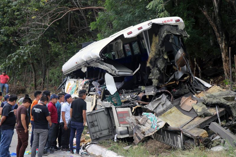 People are pictured on the scene of a collision between a passenger bus and a trailer truck early on Saturday in Gualan, near Guatemala's Atlantic coast