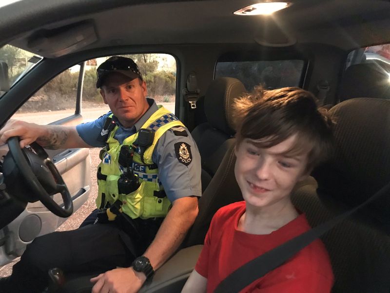 A 12 years old boy sits next to Dalwallinu Police officer S/C Smith after he drove across paddocks to escape the fire in Mogumber