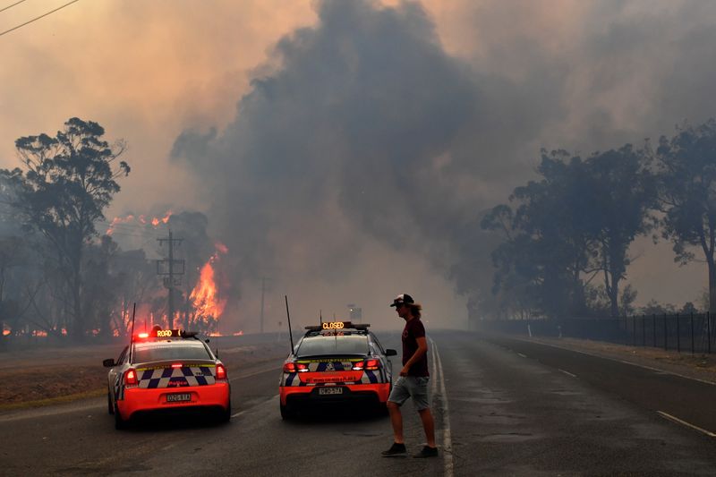 Police block the Old Hume Highway as a blaze jumps the road near the town of Tahmoor as the Green Wattle Creek Fire threatens a number of communities in the south west of Sydney