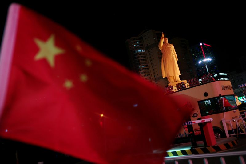 FILE PHOTO: Chinese flag flutters near a statue of late Chinese chairman Mao Zedong at a train station in Dandong