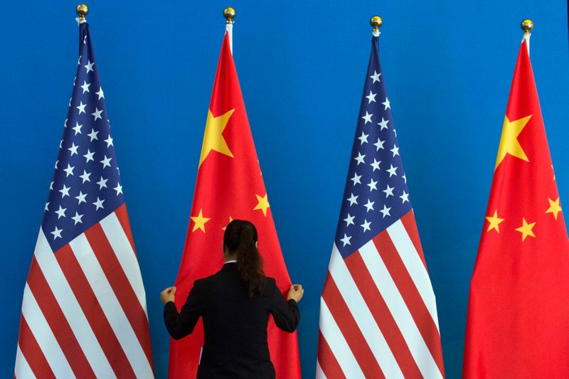FILE PHOTO: A Chinese woman adjusts a Chinese national flag next to U.S. national flags before a Strategic Dialogue expanded meeting, part of the U.S.-China Strategic and Economic Dialogue (S&ED) in Beijing