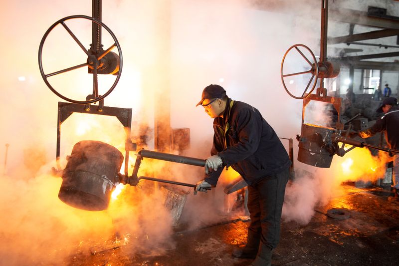 Worker pours molten iron into a mould at a mill manufacturing marine engine components in Huaian, Jiangsu