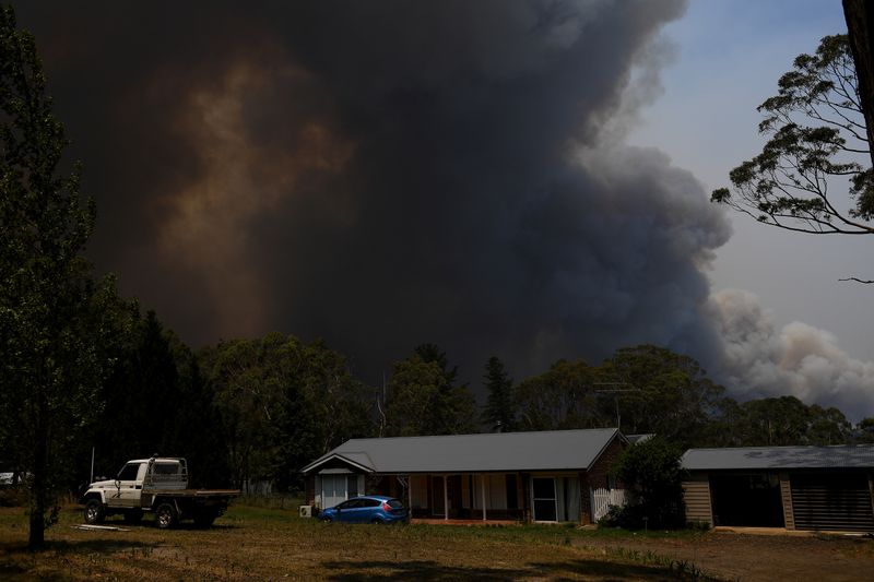 FILE PHOTO: A home is seen as smoke from the Grose Valley Fire rises in the distance, at Bilpin, New South Wales