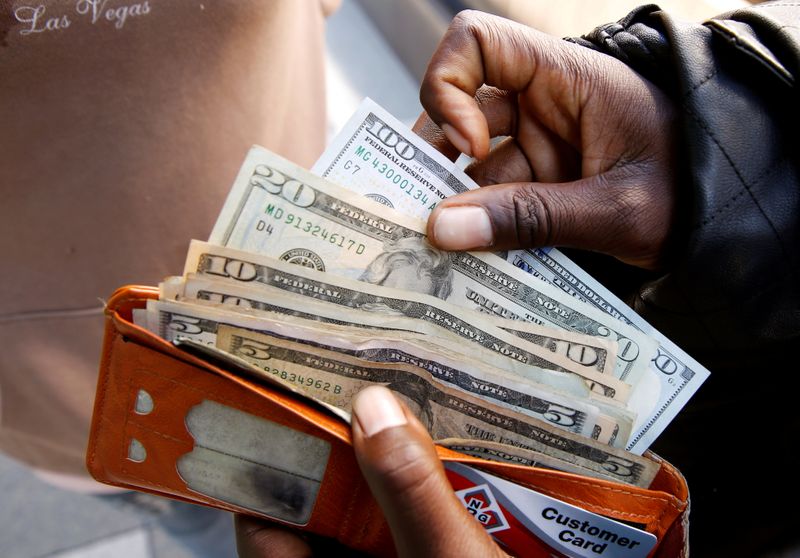 FILE PHOTO: A man displays US dollar notes after withdrawing cash from a bank in Harare