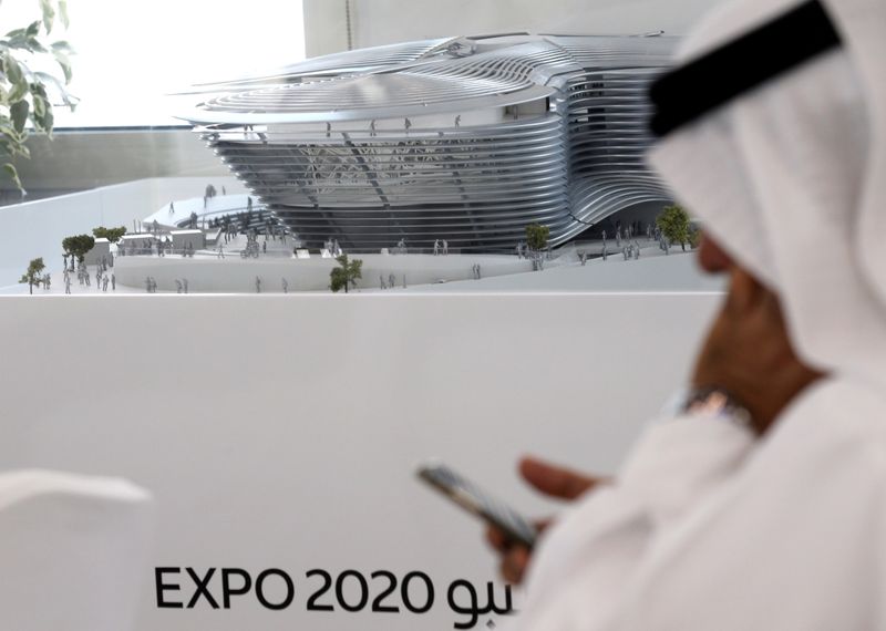FILE PHOTO: A man uses his mobile device next to a model of the Expo 2020 project in Dubai, United Arab Emirates