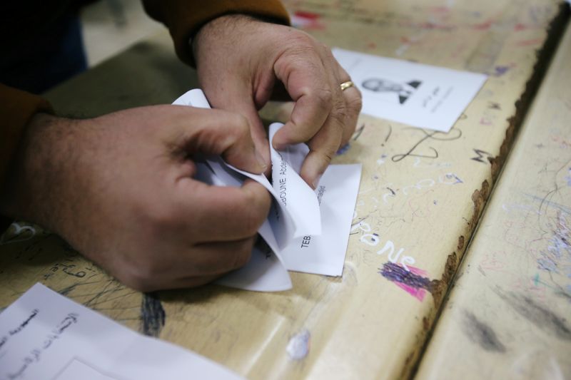 Election workers count ballots at the end of voting for presidential election at a polling station in Algiers
